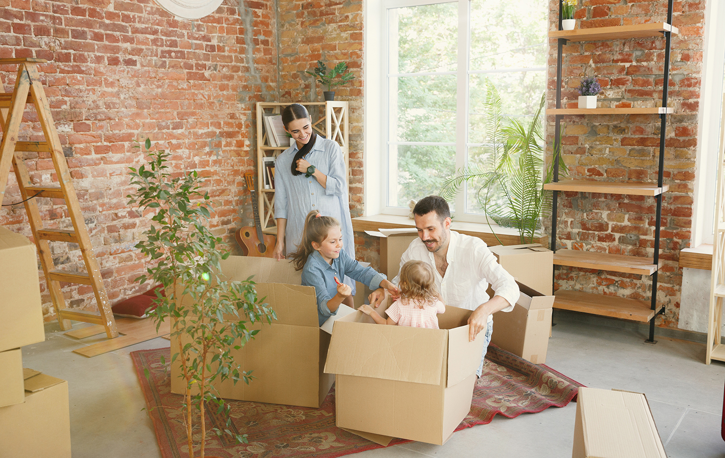 New life. Adult family moved to a new house or apartment. Spouses and children look happy and confident. Moving, relations, new life concept. Unpacking boxes with their things, playing together.